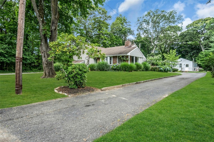 View of front of home with a chimney, a front lawn, brick siding, and asphalt driveway