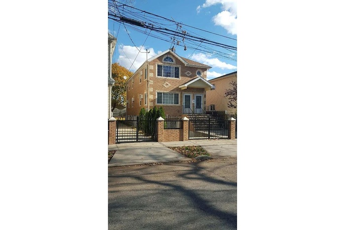 View of front facade with a gate, a fenced front yard, and brick siding