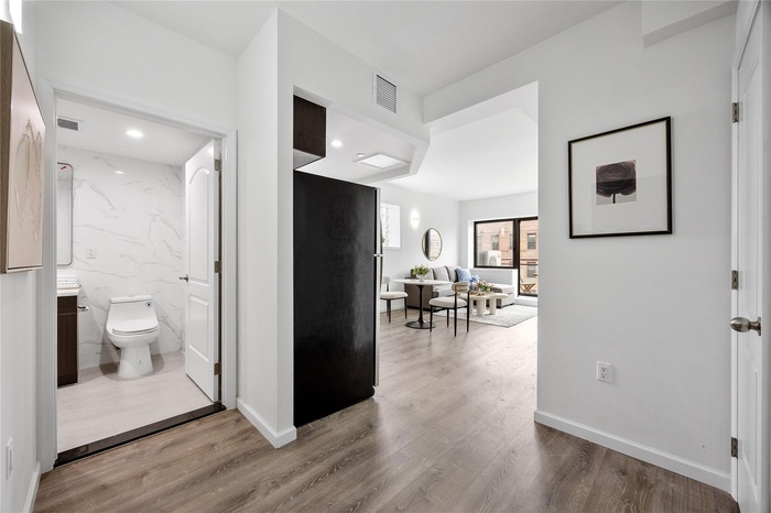 Hall with wood finished floors, baseboards, and recessed lighting