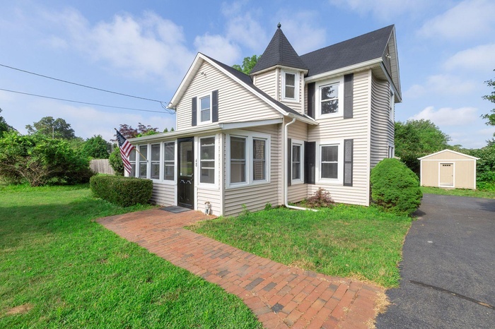 View of front of home featuring a sunroom, a front lawn, and a shed