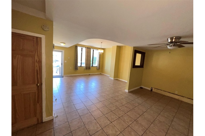Spare room with light tile patterned floors, baseboards, a chandelier, and ceiling fan