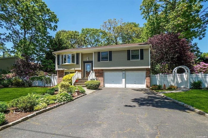 Bi-level home with driveway, a garage, and brick siding