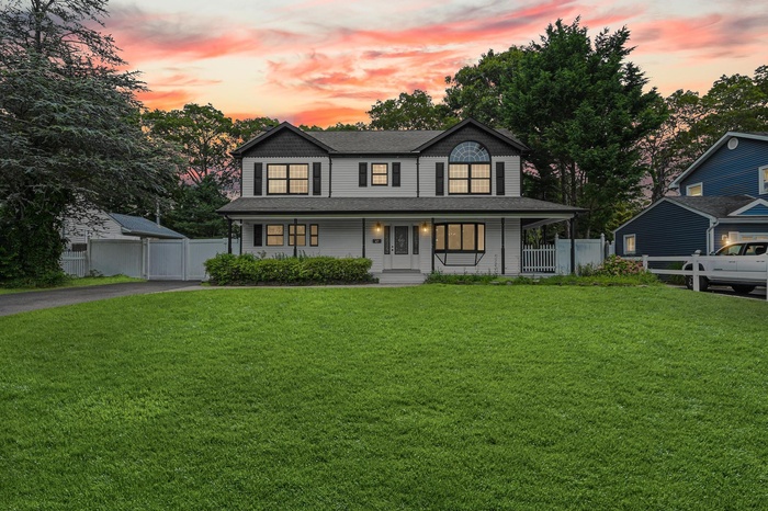 View of front of home with driveway, covered porch, and a shingled roof