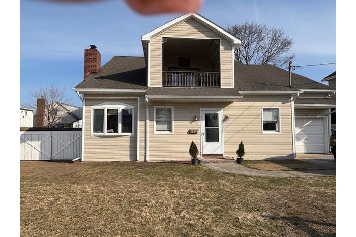 Back of house with fence, a yard, an attached garage, a balcony, and a chimney
