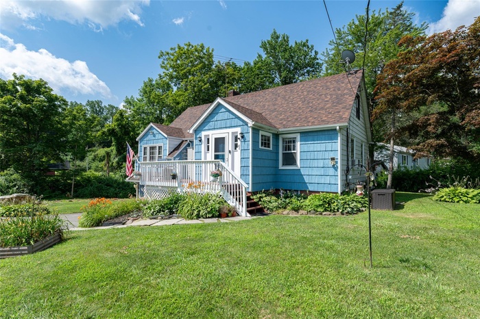 View of front of house with a shingled roof, a front yard, and a chimney