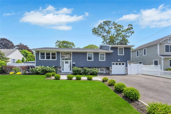 View of front of house featuring driveway, an attached garage, and stone siding