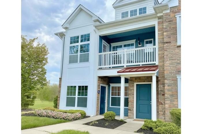 View of front facade featuring stone siding and a balcony