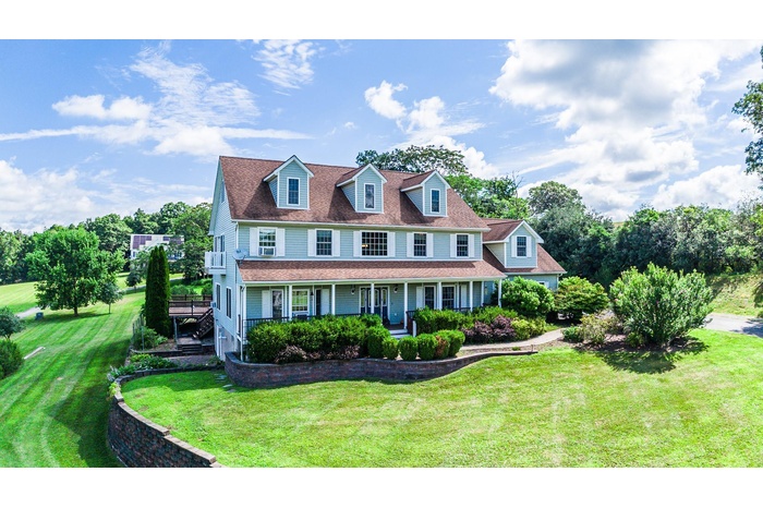 View of front of house with a front yard, a porch, and a shingled roof