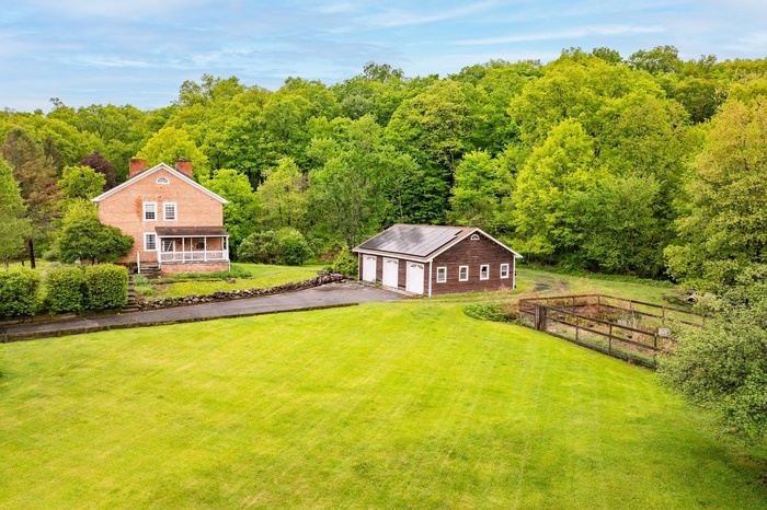 Aerial view of property and surrounding area with a heavily wooded area