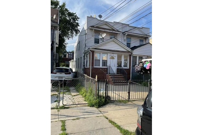 View of front facade featuring brick siding, a fenced front yard, and a gate
