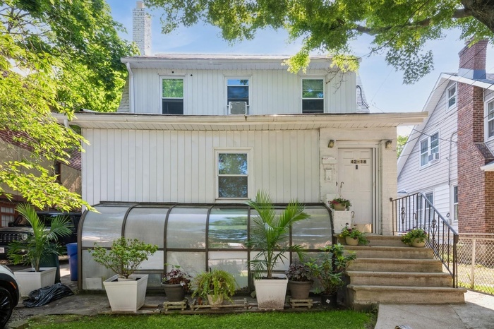 View of front of house featuring a greenhouse, a chimney, and cooling unit