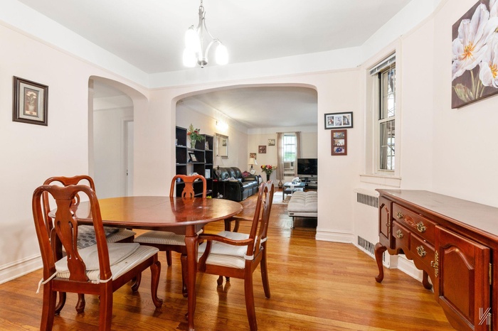 Dining room featuring arched walkways, light wood-style floors, and radiator heating unit