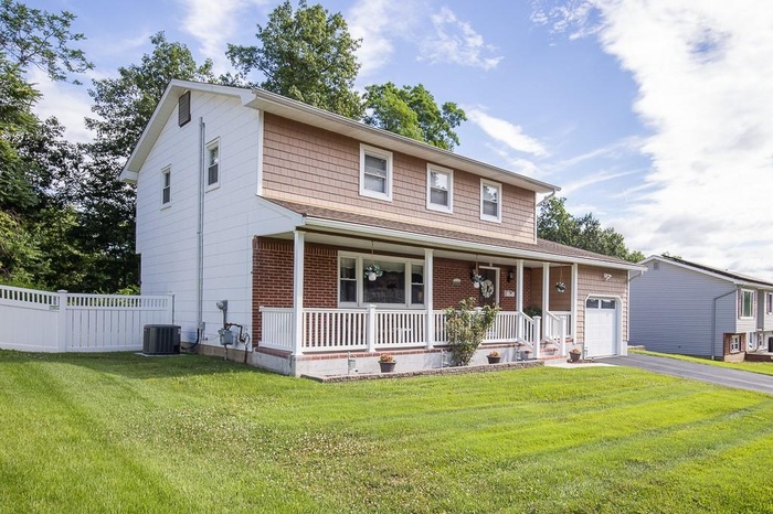 View of front of property with a porch, driveway, and garage