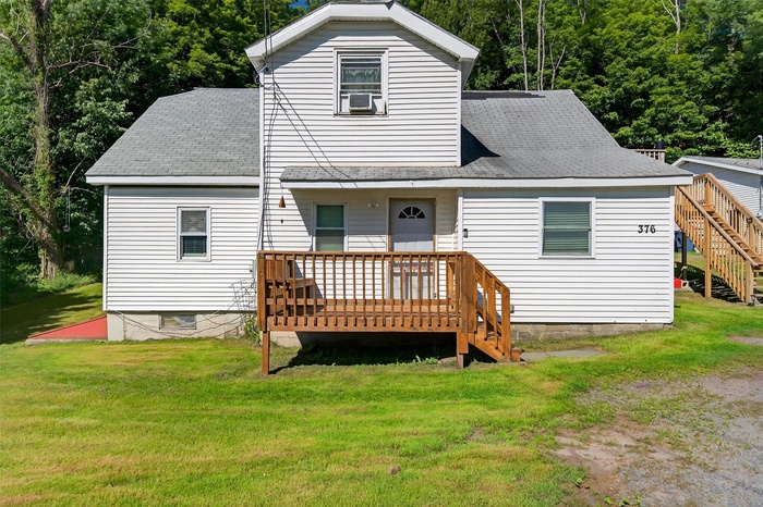 Back of house with a deck, a lawn, stairway, and a shingled roof