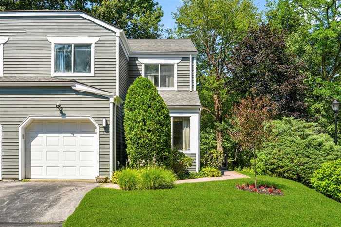 View of front facade with asphalt driveway, a front yard, an attached garage, and a shingled roof