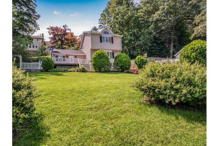 View of green lawn featuring a wooden deck