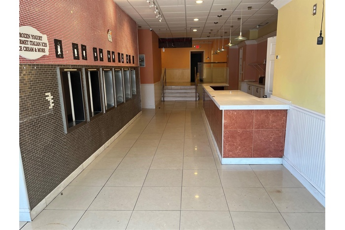 Corridor featuring a wainscoted wall, rail lighting, light tile patterned flooring, and recessed lighting