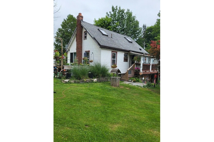 Rear view of property with a lawn, a shingled roof, a chimney, and a wooden deck