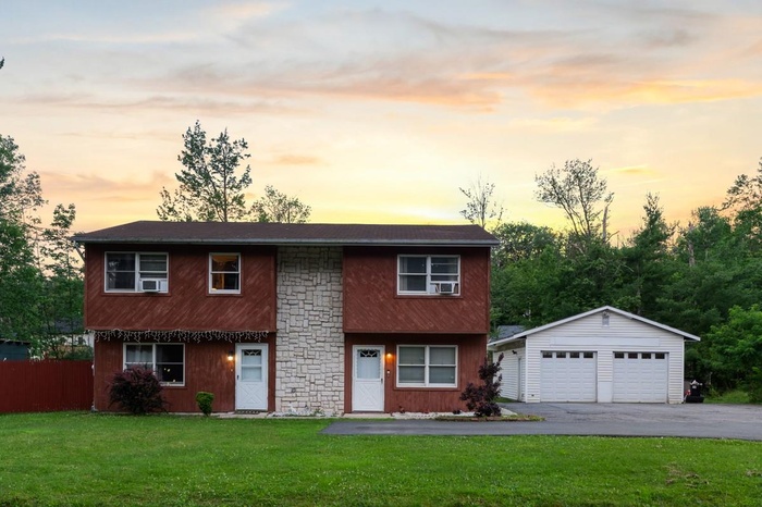 View of front of home with a detached garage and an outbuilding