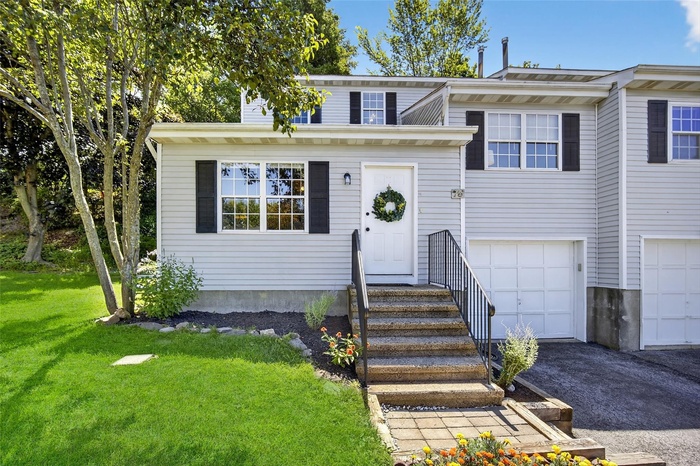 View of front facade with a front lawn, a garage, and driveway