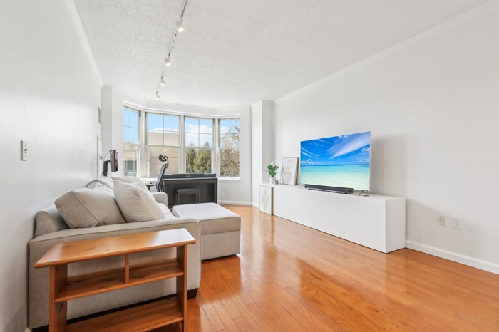 Living area with rail lighting, crown molding, baseboards, a textured ceiling, and wood finished floors