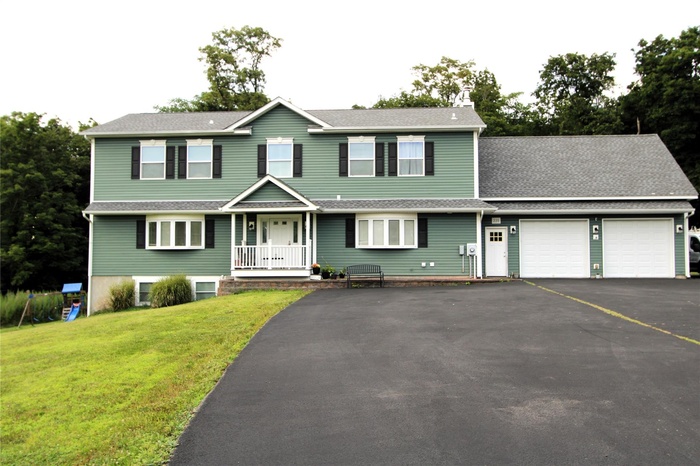 View of front facade with asphalt driveway, an attached garage, a front yard, and roof with shingles