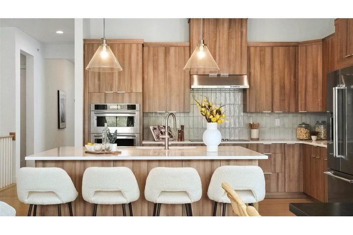 Kitchen featuring modern cabinets, appliances with stainless steel finishes, light countertops, wall chimney exhaust hood, and recessed lighting