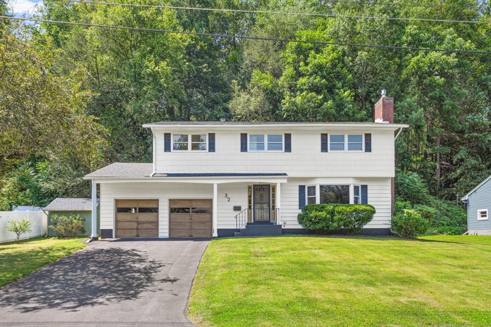 Colonial-style house with asphalt driveway, a chimney, and a garage