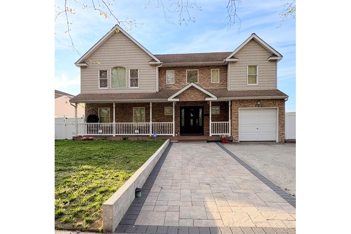 View of front of house with an attached garage, aphalt driveway, a front yard, and covered porch