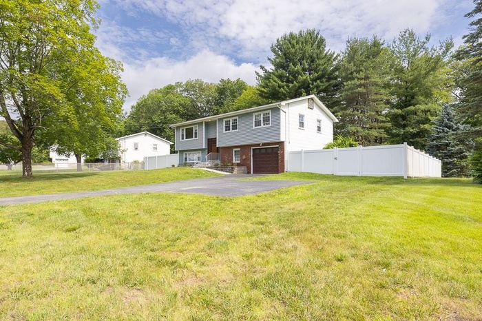 Split foyer home featuring asphalt driveway, brick siding, and an attached garage