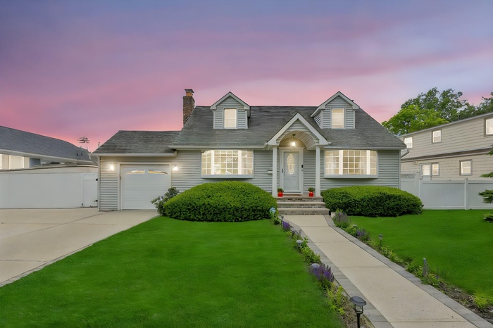 Cape cod home featuring concrete driveway, a garage, and a chimney