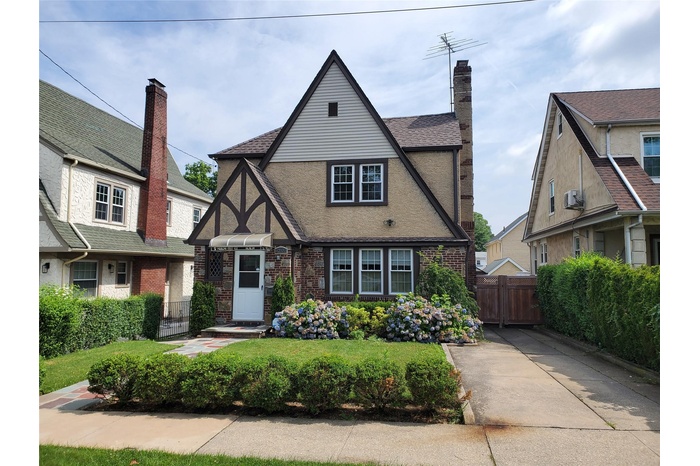 English style home with brick siding, stucco siding, and roof with shingles