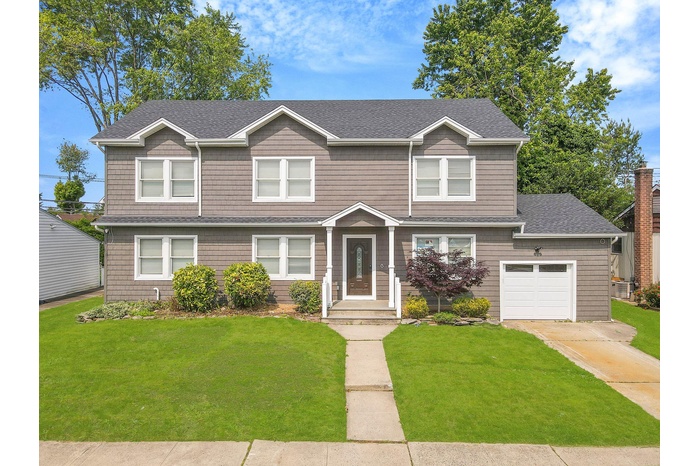 View of front of home featuring a front yard, a garage, roof with shingles, and driveway