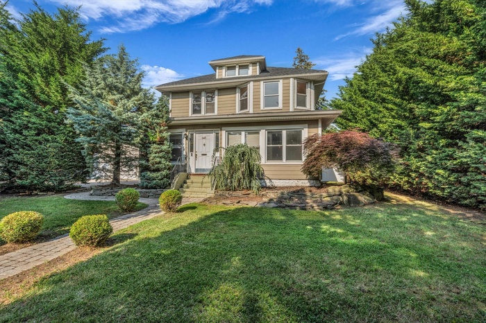 American foursquare style home featuring a front lawn