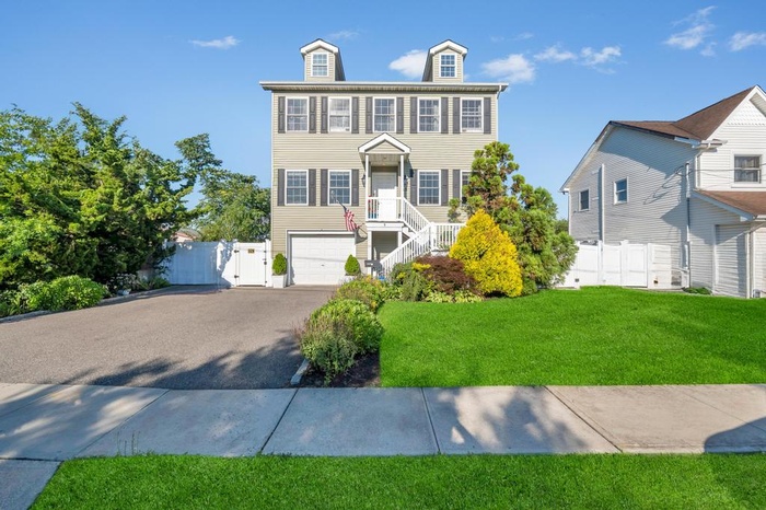 View of front facade featuring a garage, driveway, and a gate
