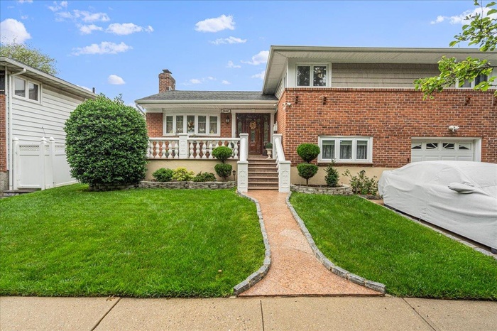 Tri-level home with brick siding, a chimney, concrete driveway, and a porch