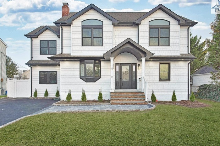 View of front of home featuring a chimney, asphalt driveway, and roof with shingles