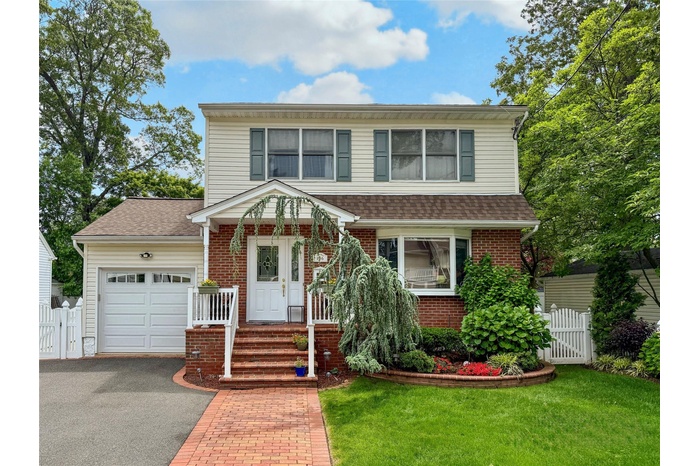 View of front of house featuring an attached garage, a gate, asphalt driveway, and brick siding