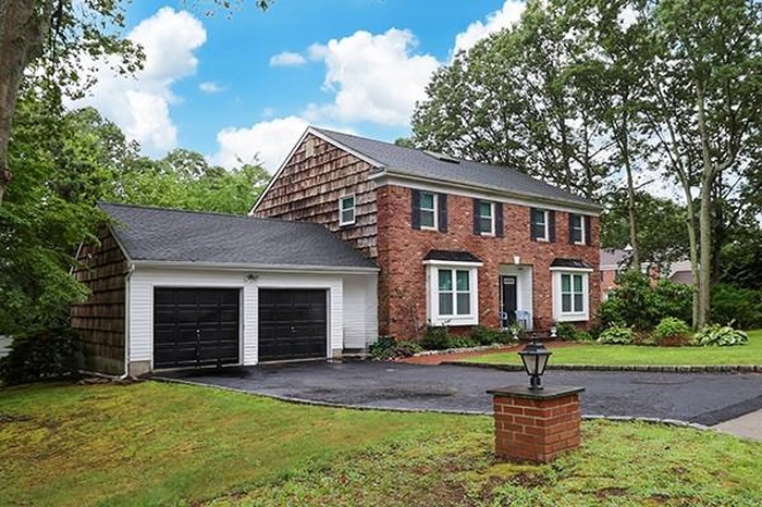 Colonial inspired home featuring an attached garage, asphalt driveway, and a front lawn