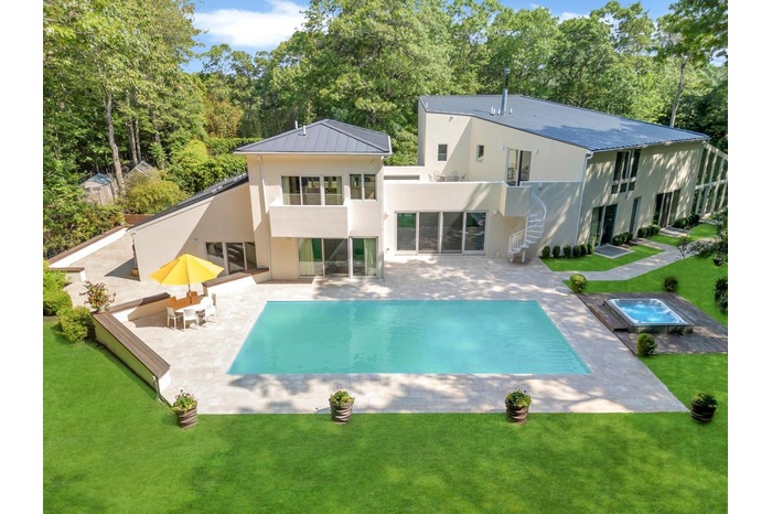 Back of house with stucco siding, a lawn, a patio, an in-ground hot tub, and a metal roof