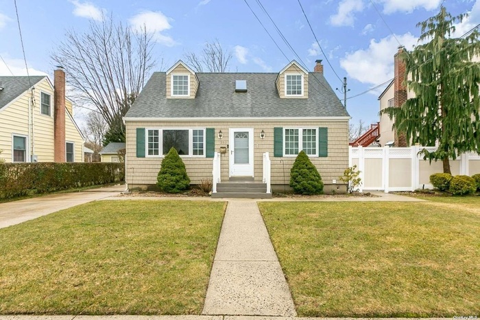 Cape cod home with a shingled roof and a chimney