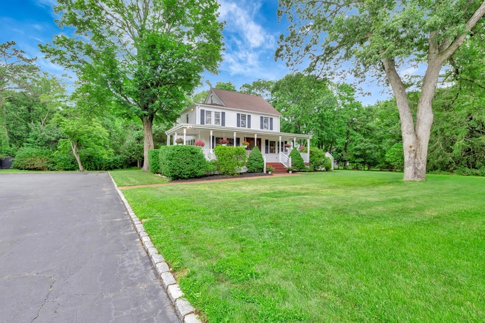 View of front of property with a porch, a front lawn, and driveway