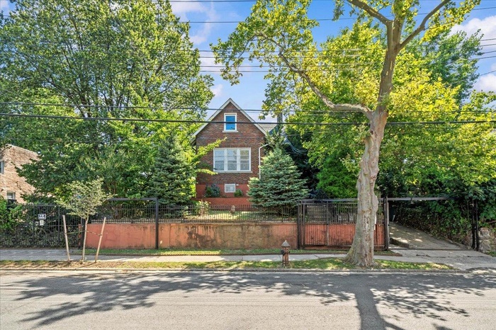 View of front of home featuring brick siding, a fenced front yard, and a gate