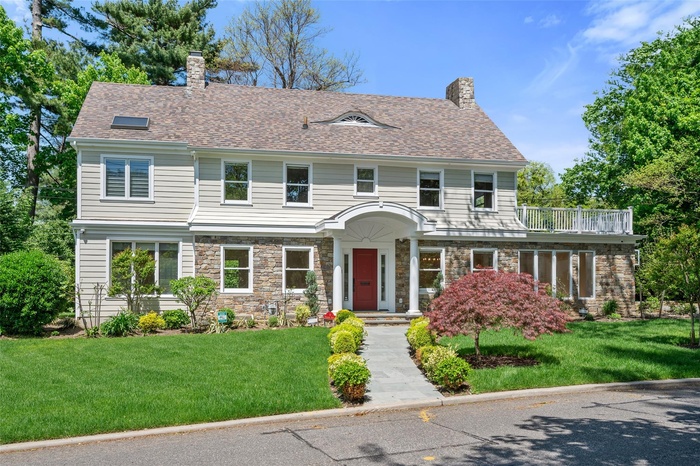 View of front of house featuring a chimney, a front lawn, and stone siding
