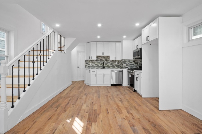 Kitchen featuring white cabinetry, tasteful backsplash, stainless steel appliances, a sink, and light wood-style flooring