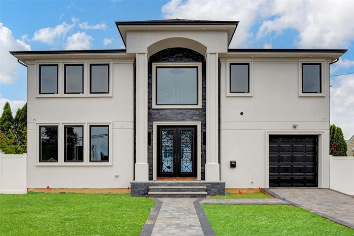 View of front of home featuring stucco siding, a garage, and driveway