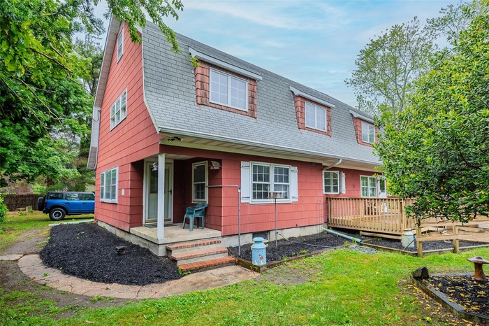 Back of property featuring a yard, a gambrel roof, a shingled roof, and a wooden deck