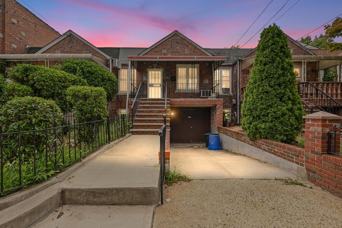View of front of property with driveway, brick siding, a porch, a garage, and stairway