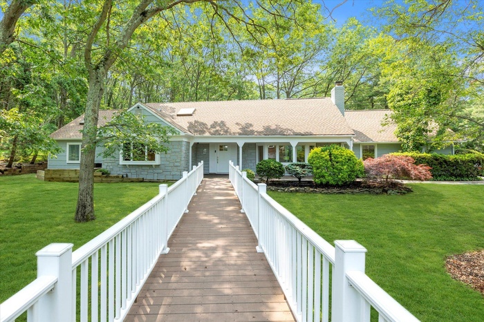 View of front of home with a front lawn, a chimney, and a shingled roof