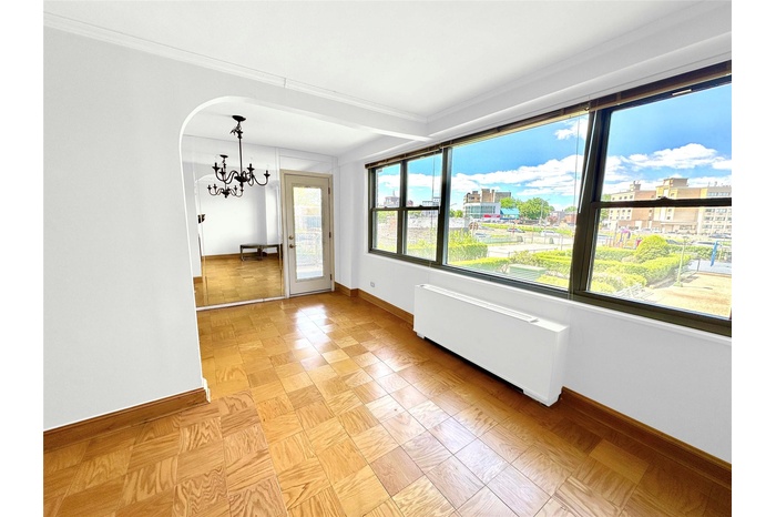 Unfurnished dining area featuring radiator heating unit, a chandelier, baseboards, crown molding, and arched walkways